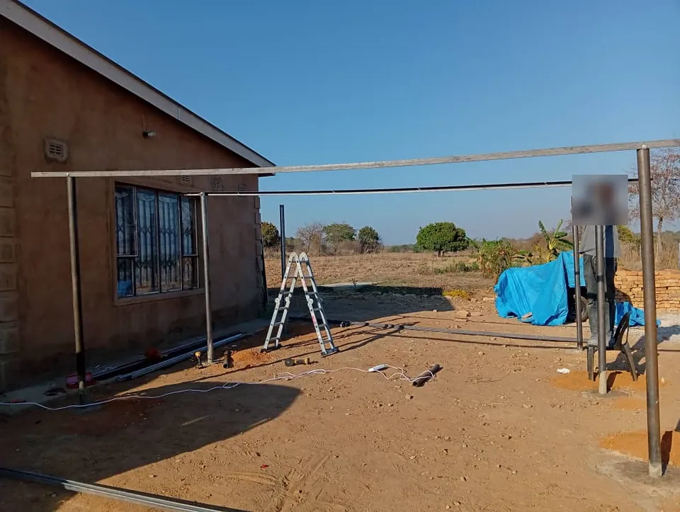 Steel carport frame being erected beside a house